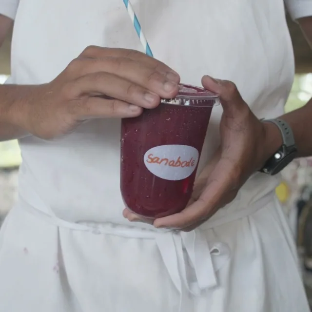A red fruit blend held up in a Sanabode cup